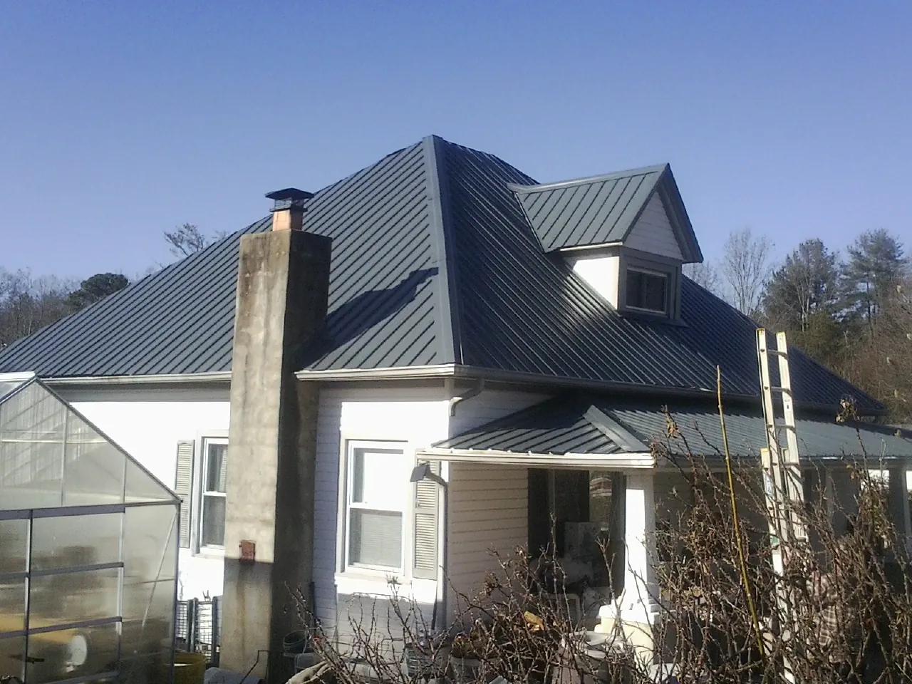 Dark blue standing seam metal roof on a white farmhouse with dormer — Slate & Tile Roof Repair by Roofing Brothers in Ridgefield