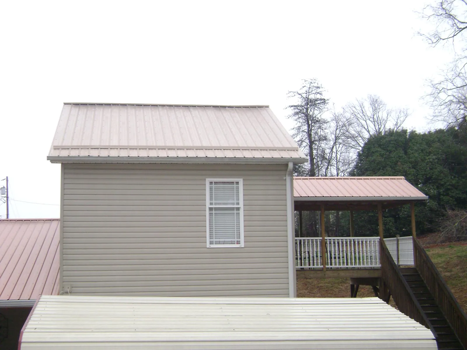 Tan metal roofs on a two story addition and attached porch, from a Roof Replacement job in Ridgefield