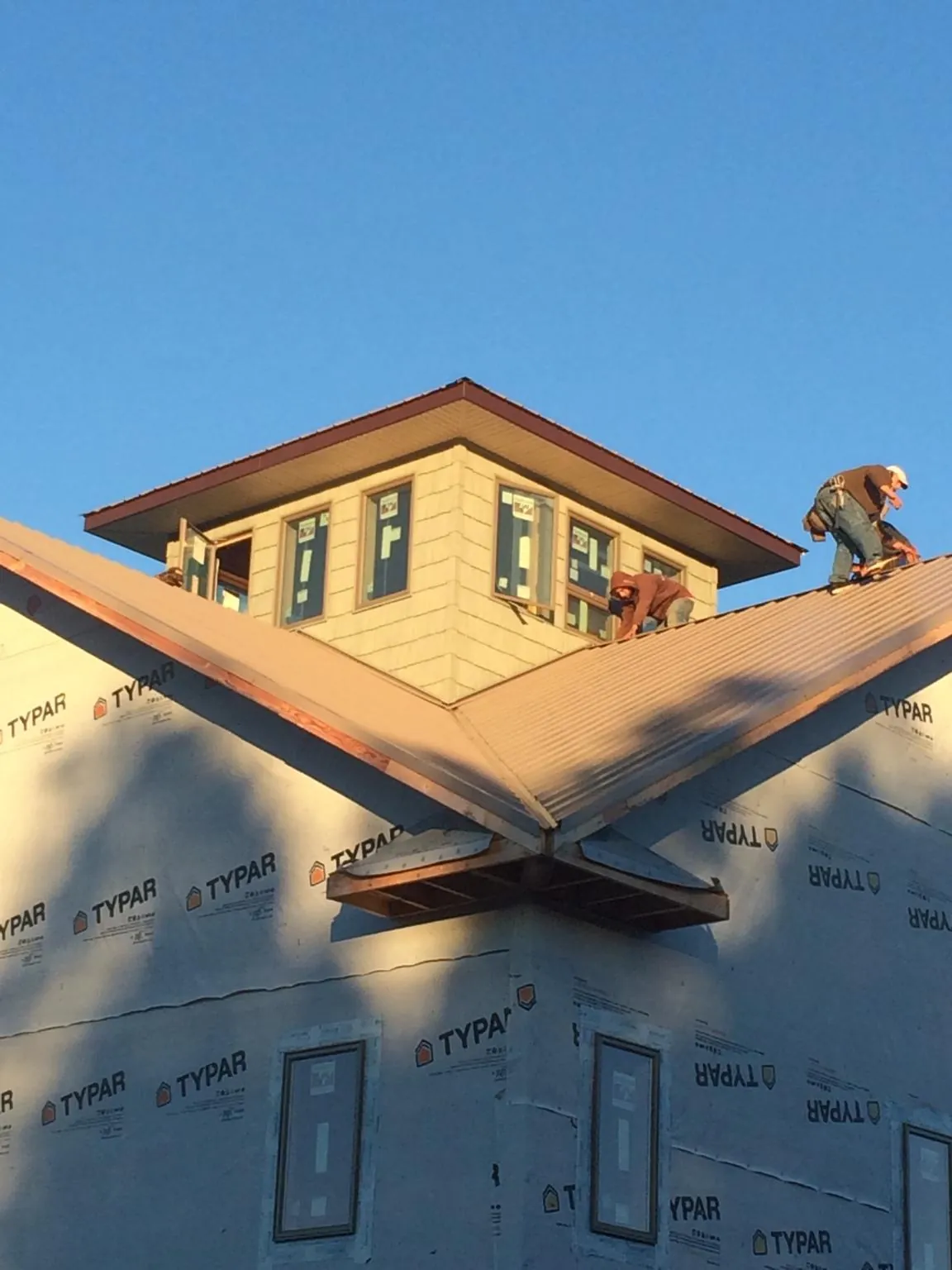 Roofers working around a rooftop cupola on a new metal roof at sunset — Roof Waterproofing in Ridgefield by Roofing Brothers